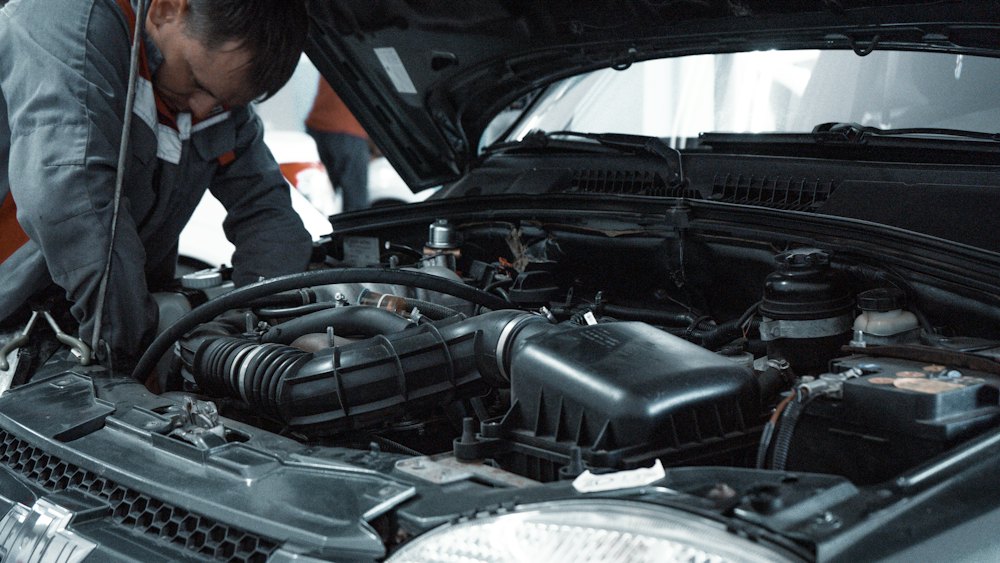 M&eacute;canicien inspectant le moteur d’une voiture dans un garage